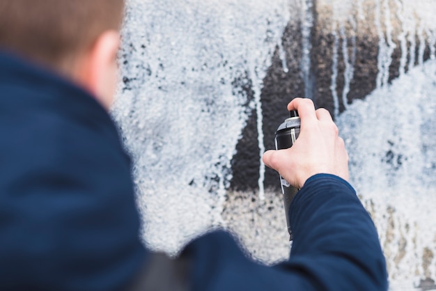 man-using-spray-drawing-graffiti-wall_23-2147839425